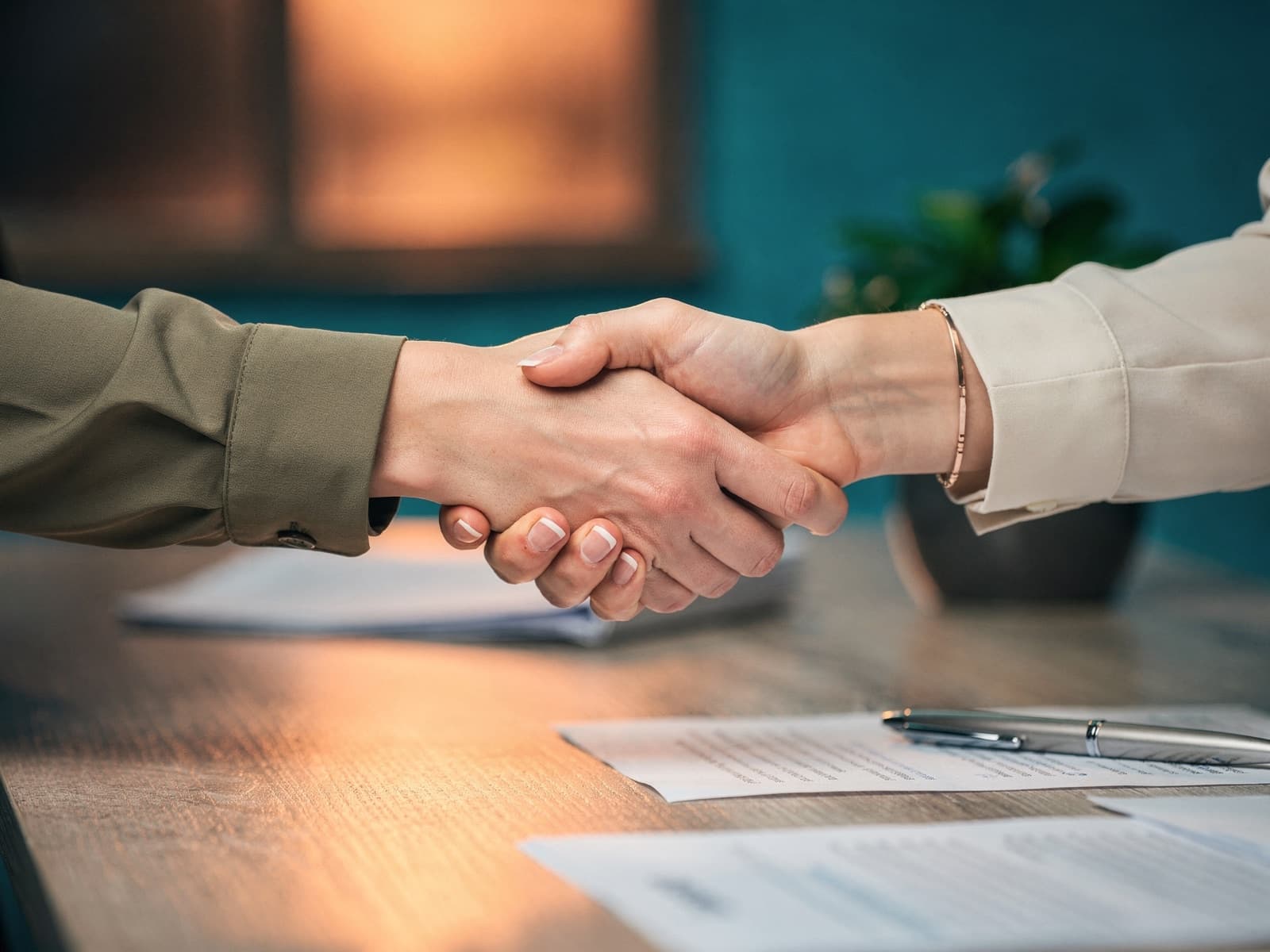 Zwei Personen geben sich am Schreibtisch die Hand